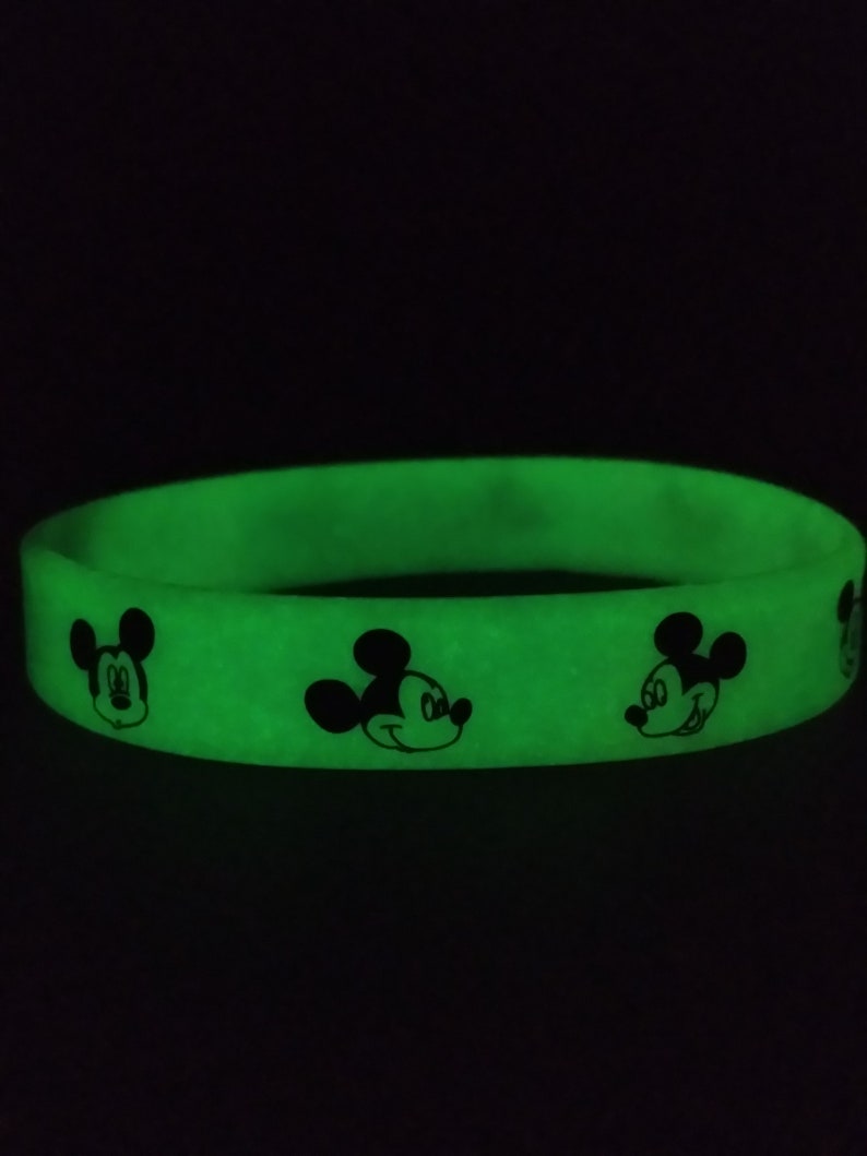 Puede incluir: Una pulsera de silicona verde brillante con dise&ntilde;os negros del personaje de Mickey Mouse. La pulsera es de color liso con la cara del personaje de dibujos animados impresa alrededor. La pulsera es un accesorio divertido.