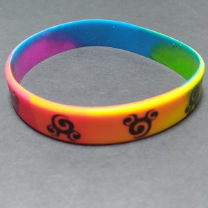 Op de afbeelding: Een regenboog siliconen armband met zwarte swirl-ontwerpen.