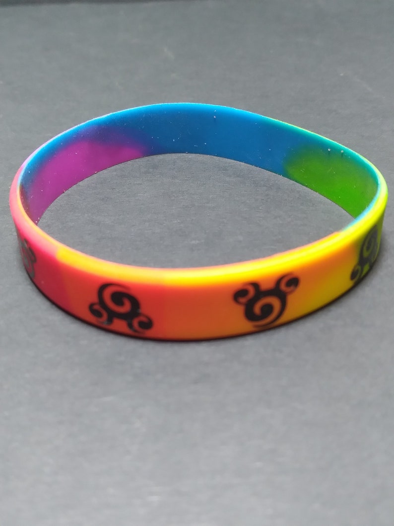 Op de afbeelding: Een regenboog siliconen armband met zwarte swirl-ontwerpen.