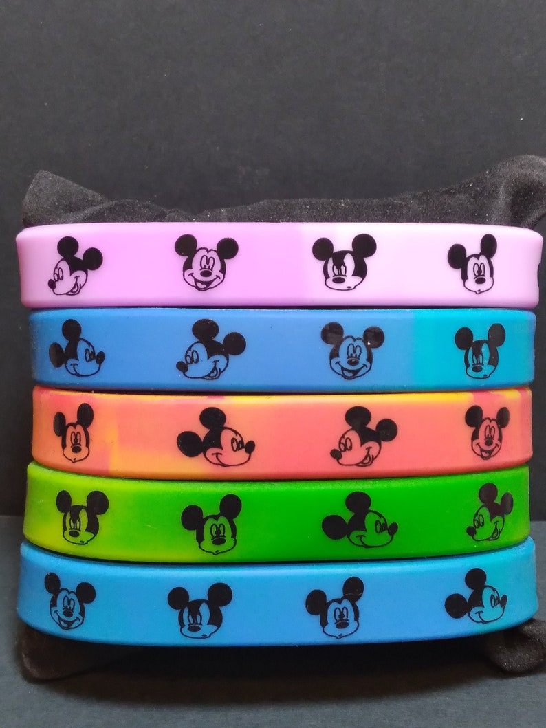 Puede incluir: Un conjunto de seis pulseras de silicona de colores con un dise&ntilde;o de silueta de Mickey Mouse negro. Las pulseras son en tonos de rosa, azul, naranja y verde.