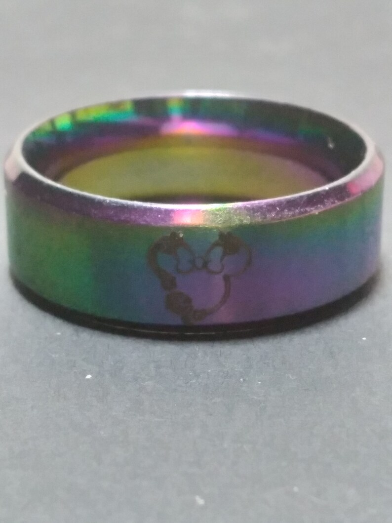 May include: A rainbow iridescent stainless steel ring with a Mickey Mouse silhouette engraved on the band.