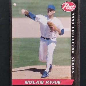 May include: A 1993 Collector Series baseball card featuring Nolan Ryan of the Texas Rangers in a pitching pose. The card has a red and white banner at the bottom with the player's name and team.