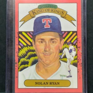 May include: A baseball card featuring Nolan Ryan, with the text "King of Kings" and "Donruss" at the top. The card has a portrait of Ryan wearing a blue baseball cap with a white "T" and a smaller image of a baseball player pitching.