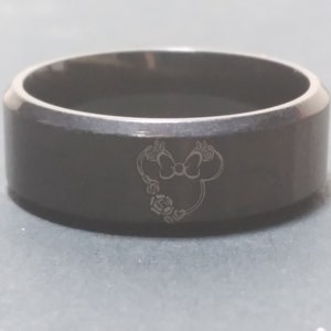 May include: A black stainless steel ring with a laser-engraved design of a cartoon mouse head with a bow and flowers.