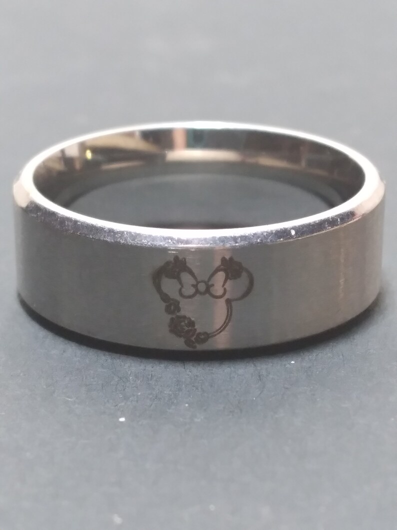 May include: A silver ring with a Mickey Mouse head engraved on the band.