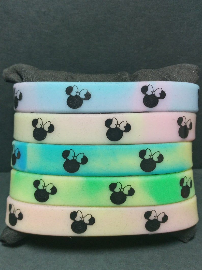 May include: A stack of six colorful silicone bracelets with a black and white Minnie Mouse design. The bracelets are in shades of blue, pink, green, and yellow.