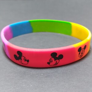 Puede incluir: Una pulsera de silicona arco&iacute;ris con tres caras de Mickey Mouse en blanco y negro.