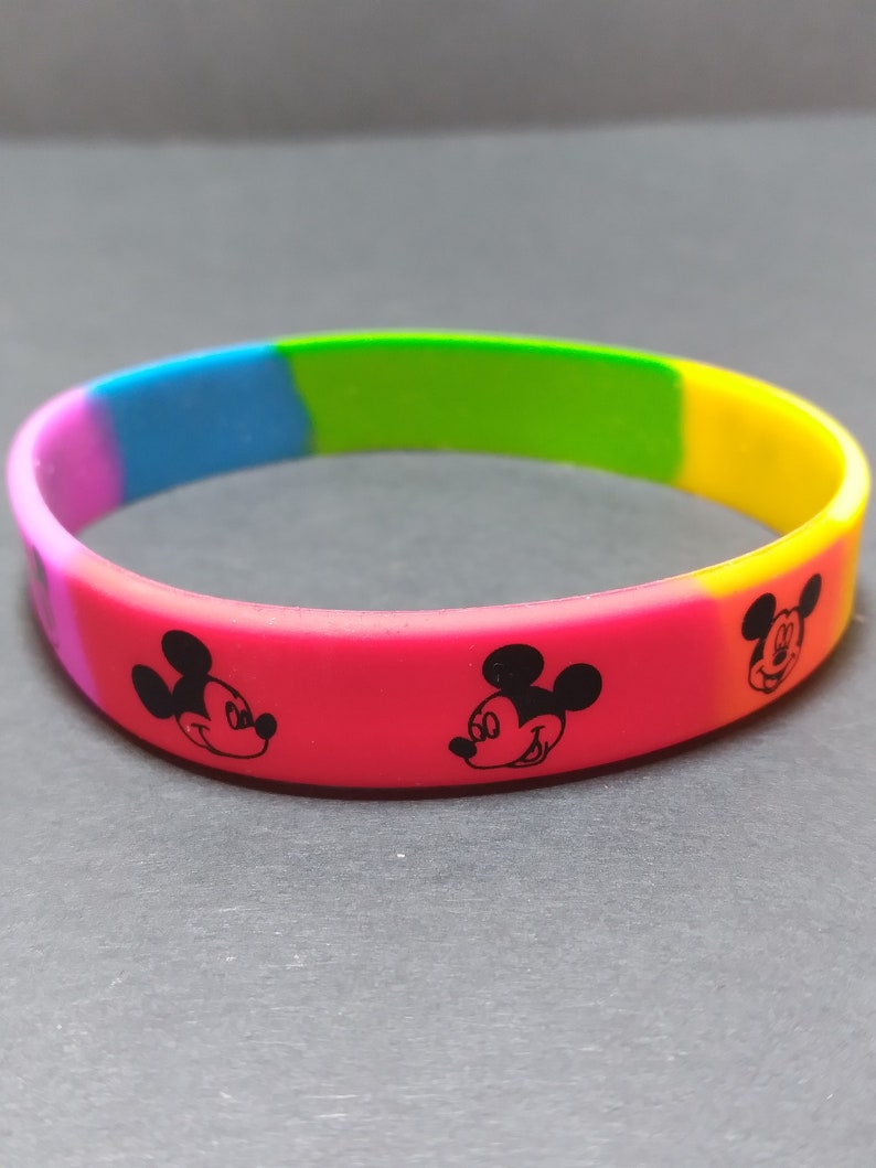 Puede incluir: Una pulsera de silicona arco&iacute;ris con tres caras de Mickey Mouse en blanco y negro.