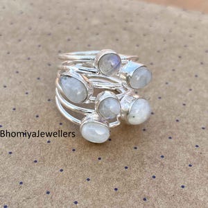 Op de afbeelding: Een set van vijf zilveren ringen met maansteen edelstenen. De ringen zijn op elkaar gestapeld, met de maansteen naar buiten gericht. De ringen zijn van een delicaat en elegant ontwerp.