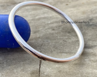 May include: A silver bangle bracelet, a simple and classic design. The bracelet is smooth and shiny, with a rounded shape.  Bhomiyajewellers.