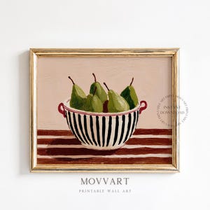 May include: A framed print of a still life featuring a bowl of green pears. The bowl has black and white vertical stripes and red handles. The background is a light pink with brown and white stripes at the bottom. The text "MOVART PRINTABLE WALL ART" is at the bottom.