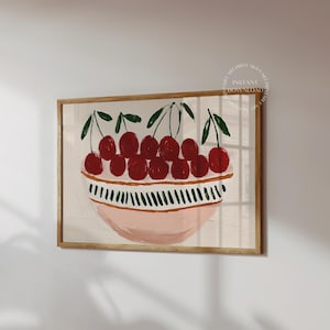 May include: A framed art print featuring a still life of cherries in a bowl. The cherries are a vibrant red with green stems, set against a light pink and white bowl. The bowl has a decorative design. The artwork is in a wooden frame.