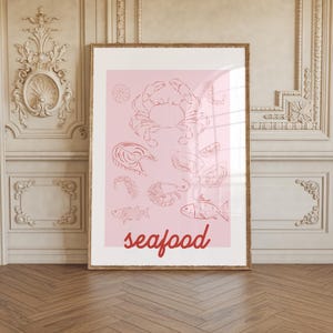 Op de afbeelding: Een roze en rode printbare kunstprint met verschillende illustraties van zeevruchten, waaronder een krab, vissen, garnalen en oesters. De tekst "seafood" staat in rood onderaan de print.