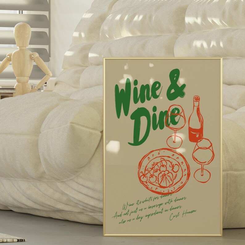 以下が含まれることがあります： ベージュの背景に緑色の文字で「Wine & Dine」と書かれた額装されたプリント。プリントには、赤いイラストで描かれた料理の盛り合わせ、ワインボトル、ワイングラス2つが描かれている。