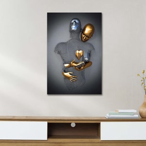 May include: Abstract metal sculpture of two figures embracing, one silver and one gold, with a gold heart in the center. The sculpture is displayed on a white wall above a wooden entertainment center.