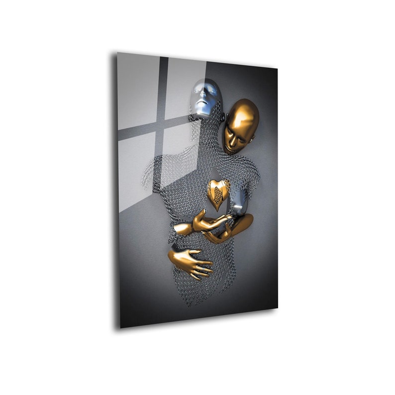 May include: Abstract sculpture of two figures embracing, one silver and one gold, with a gold heart in the center. The figures are made of wire mesh and have a modern, minimalist style.