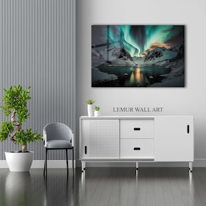 K&ouml;nnte beinhalten: Ein Wandbild mit einer leuchtend gr&uuml;nen und blauen Aurora Borealis &uuml;ber einer schneebedeckten Bergkette und einem stillen See. Der Druck ist gerahmt und h&auml;ngt an einer wei&szlig;en Wand &uuml;ber einem wei&szlig;en Schrank mit einer Holzplatte.