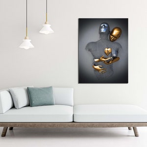 May include: Abstract metal sculpture of two figures embracing, one silver and one gold, with a gold heart in the center. The sculpture is mounted on a dark gray background.