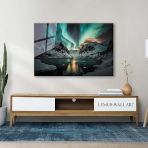 K&ouml;nnte beinhalten: Ein Wandbild mit einer malerischen Landschaft mit einem See, Bergen und einer leuchtend gr&uuml;nen Aurora Borealis am Himmel. Das Kunstwerk ist an einer Wand &uuml;ber einem h&ouml;lzernen Unterhaltungszentrum mit einer wei&szlig;en Schublade und einem Regal angebracht. Das Unterhaltungszentrum steht auf einem blauen Teppich.