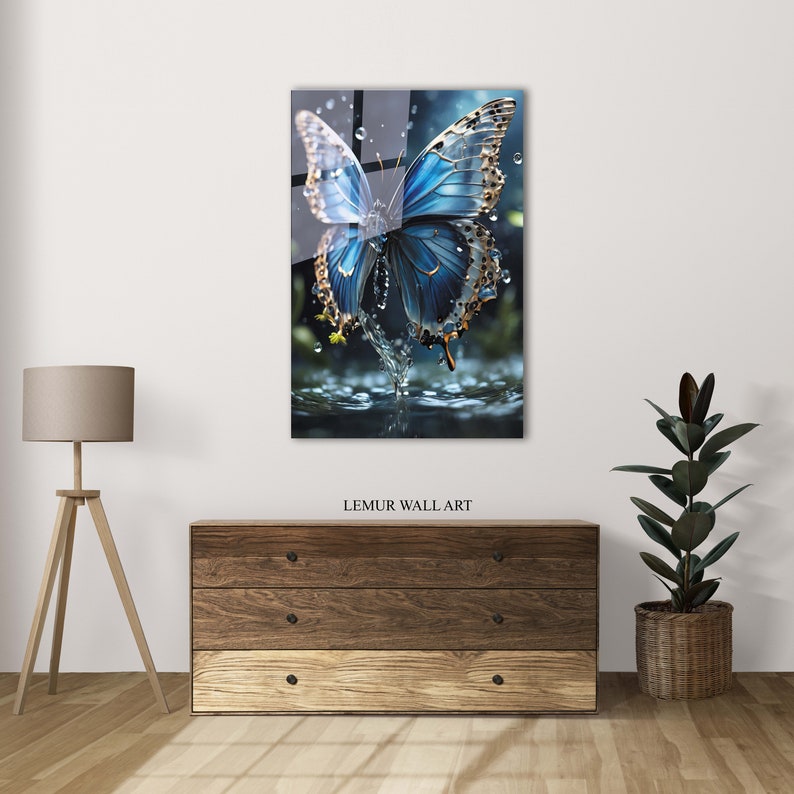 May include: A blue butterfly with gold accents is perched on a water surface with water droplets falling around it. The butterfly's wings are spread wide, and the water is reflecting the light.
