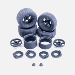 May include: A set of four gray plastic model car wheels with tires, two gray plastic model car wheel hubs, two gray plastic model car brake rotors, and two gray plastic model car valve stem caps.