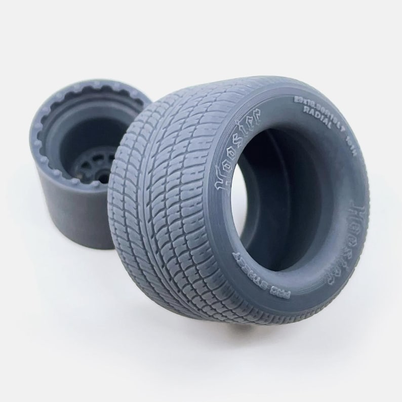 May include: Gray model car tire with the text "Hoosier" and "Radial" printed on the side.