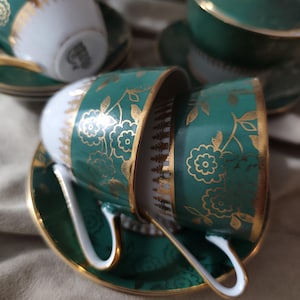 Könnte beinhalten: Set aus drei Keramikbechern mit gesprenkelter, matter Oberfläche. Die Becher sind in Creme-, Hellgrau- und Dunkelgrautönen gehalten. Jede Tasse hat ein schlichtes, minimalistisches Design.