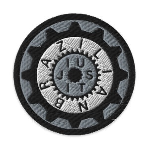 May include: Black and white embroidered patch with a gear design. The center of the gear has a smaller gear with the words "JUST DO IT" written around it.
