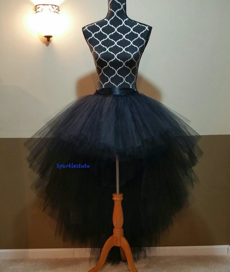 Puede incluir: Falda de tul negro de alta y baja con una cintura de sat&eacute;n negro. La falda est&aacute; en capas y tiene una cola larga en la parte posterior. La falda est&aacute; en un maniqu&iacute;.