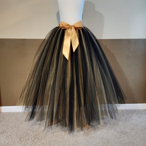 May include: A black and gold tulle skirt with a gold satin bow at the waist.