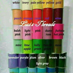 May include: A display of various colors of tulle fabric rolls, including white, pink, green, and blue. Each roll is labeled with its color name. The text "Lisa's Threads" is also visible.