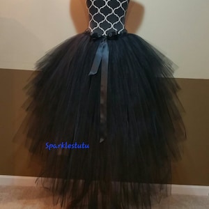 Puede incluir: Falda de tul negro con una cola larga y un lazo de sat&eacute;n negro para atar. La falda est&aacute; en capas y tiene una silueta completa y fluida. La falda est&aacute; en un maniqu&iacute;.