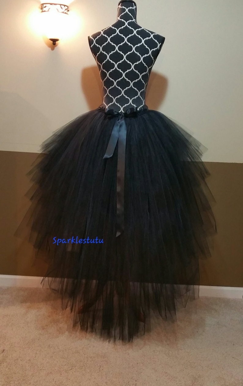 Puede incluir: Falda de tul negro con una cola larga y un lazo de sat&eacute;n negro para atar. La falda est&aacute; en capas y tiene una silueta completa y fluida. La falda est&aacute; en un maniqu&iacute;.