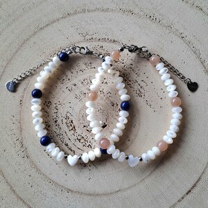 Peut inclure: Deux bracelets délicats avec des perles blanches, bleues et roses. Les bracelets sont faits de petites perles blanches rondes, entrecoupées de perles bleues et roses. Les bracelets ont une chaîne et un fermoir argentés.