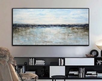 May include: Abstract landscape painting with a blue and brown color scheme. The painting depicts a horizon with a body of water in the foreground. The painting is framed in a black frame and is hanging on a wall in a modern living room.