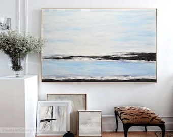 May include: Abstract landscape painting with a blue and white color scheme. The painting features a horizontal line representing a horizon with a dark blue band representing water. The painting is framed and hanging on a white wall.