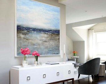 May include: A large abstract painting of a seascape with blue and gray tones. The painting is hanging above a white dresser with three drawers. There are pink flowers in vases on the dresser.