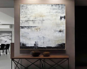 May include: Abstract painting with a gold frame. The artwork features a textured surface with a palette of white, black, and beige. The painting is displayed above a wooden console table with a black metal base, and two decorative vases.
