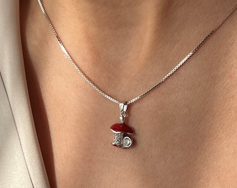 May include: A silver chain necklace with a small red and white mushroom pendant.