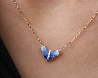 May include: A gold chain necklace with a blue and white enamel butterfly pendant.