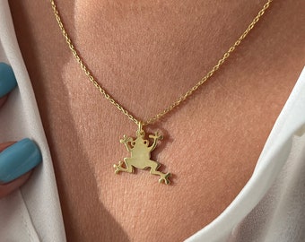 May include: A gold chain necklace with a frog pendant. The frog is facing forward with its legs outstretched.