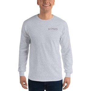 以下が含まれることがあります： クルーネックのライトグレーの長袖Tシャツで、左胸上部にダークグレーのフォントでK75Sという文字がプリントされています。この衣類は杢調の生地で作られており、長袖でストレートな裾のスタンダードなフィット感のデザインです。