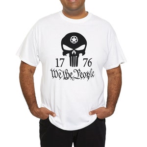 Op de afbeelding: Wit T-shirt met een zwarte schedel afbeelding en de tekst "1776 We the People".