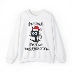May include: White long-sleeved sweatshirt with a black cat wearing a Santa hat and Christmas lights. The text "It's Fine I'm Fine Everything is Fine" is printed on the sweatshirt.
