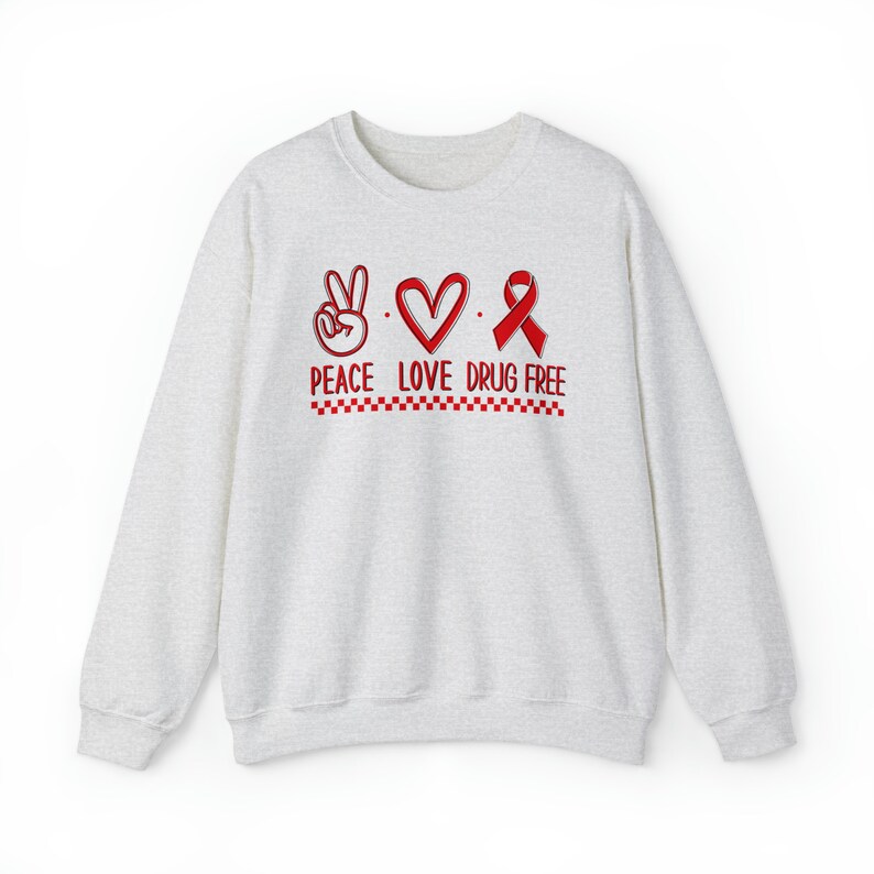May include: A light gray sweatshirt with a red peace sign, heart, and ribbon. The text "Peace Love Drug Free" is printed below the symbols.