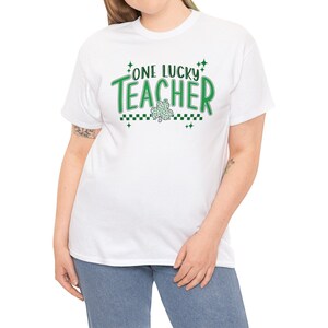 Puede incluir: Camiseta blanca con texto verde que dice "One Lucky Teacher" y un tr&eacute;bol verde.