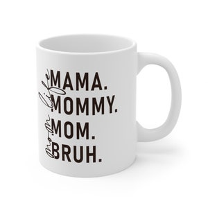 May include: White ceramic coffee mug with black text that reads "Mama. Mommy. Mom.  Bruh."