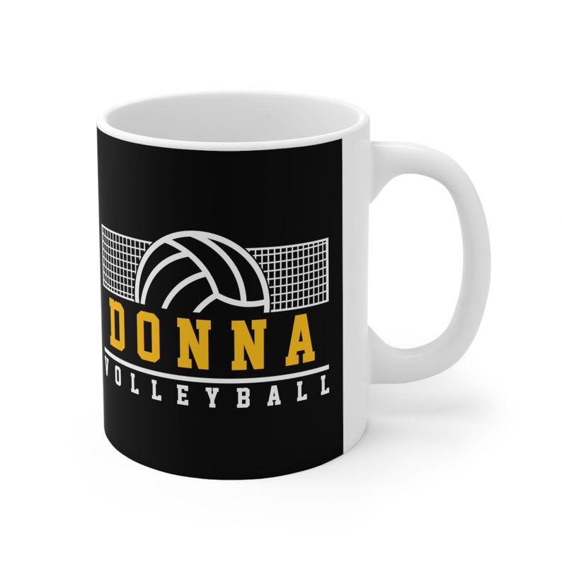 May include: White ceramic mug with a black background. The mug features a white volleyball graphic with a net, the word "DONNA" in yellow letters, and the text "VOLLEYBALL" in white letters.