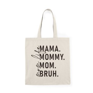 May include: A beige tote bag with black text that reads "Mama. Mommy. Mom.  Bruh."