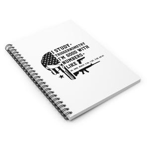 May include: White spiral-bound notebook with black text and graphics. The text reads "I STUDY TRIGGERNOMETRY I'M GOOD WITH NUMBERS LIKE" with images of guns and the American flag. The notebook is angled, showing the spiral binding.